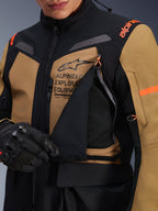 Alpinestars ST-7 2L GORE-TEX jakke, adventure touring motorcykeljakke, Gobi brun og sort, nærbillede af det åbne ventilationspanel på brystet, der afslører åndbart mesh, med Alpinestars Exploration Equipment branding og orange detaljer.