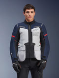 Alpinestars ST-7 2L GORE-TEX jakke, adventure touring motorcykeljakke, isgrå og mørkeblå med røde detaljer, vandtæt og åndbar, båret af en model med sorte handsker, med Alpinestars Exploration Equipment-branding på brystet