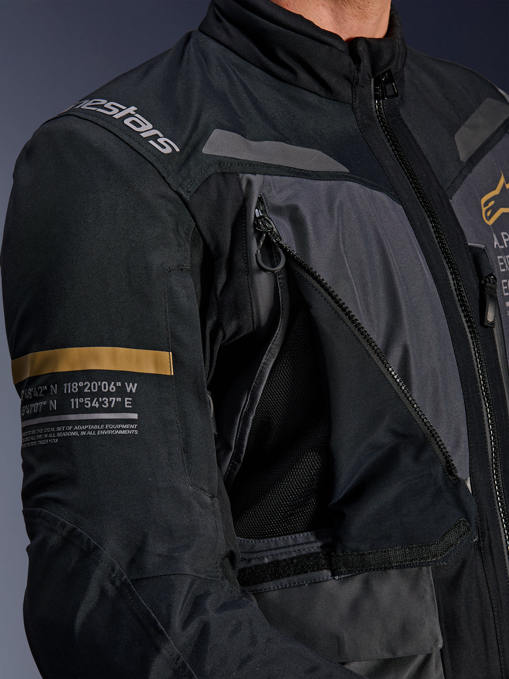 Alpinestars ST-7 2L GORE-TEX jakke, mørkegrå og sort, nærbillede af åbent ventilationspanel på brystet med lynlås og mesh, Alpinestars-logo på skulderen, khaki-stribe på ærmet med trykte geografiske koordinater, teknisk adventure-touring motorcykeludstyr