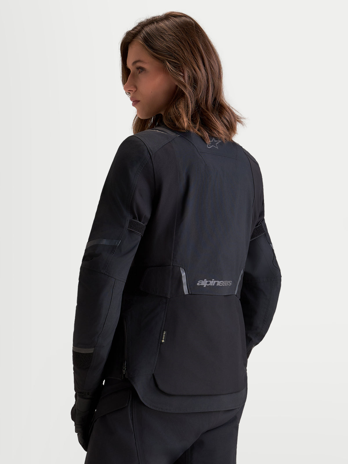 Alpinestars Stella St-7 V2 2L Gore-Tex Jacket, women's adventure touring motorcycle jacket in black, rear three-quarter view worn by a model showing waterproof textile construction and reflective branding details