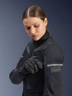 Alpinestars Stella ST-7 2L GORE-TEX jakke til damer, adventure road-touring jakke, sort og mørkegrå, båret af en kvinde, der justerer en detalje på ærmet, med refleksstriber og koordinatgrafik, holdbar tekstilskal til kørsel i alle sæsoner