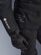 Alpinestars Dame Stella ST-7 2L GORE-TEX Jakke, sort adventure-touringjakke, nærbillede af ærme med hvidt GORE-TEX-logo, Alpinestars Exploration Equipment-tekst på hoften, sort motorcykelhandske, vandtæt tekstilmateriale med funktionelle cargolommer