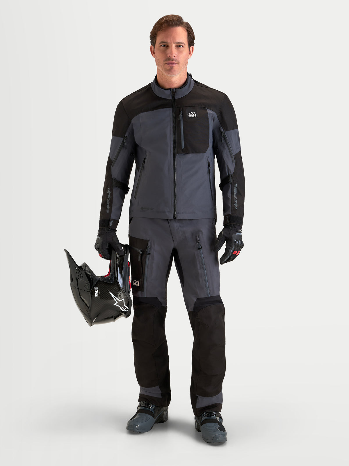 Alpinestars Arenis Gore-Tex Pants, men's adventure touring motorcycle pants in black and deep gray, front view on a model wearing matching gear, helmet, and waterproof textile riding apparel.