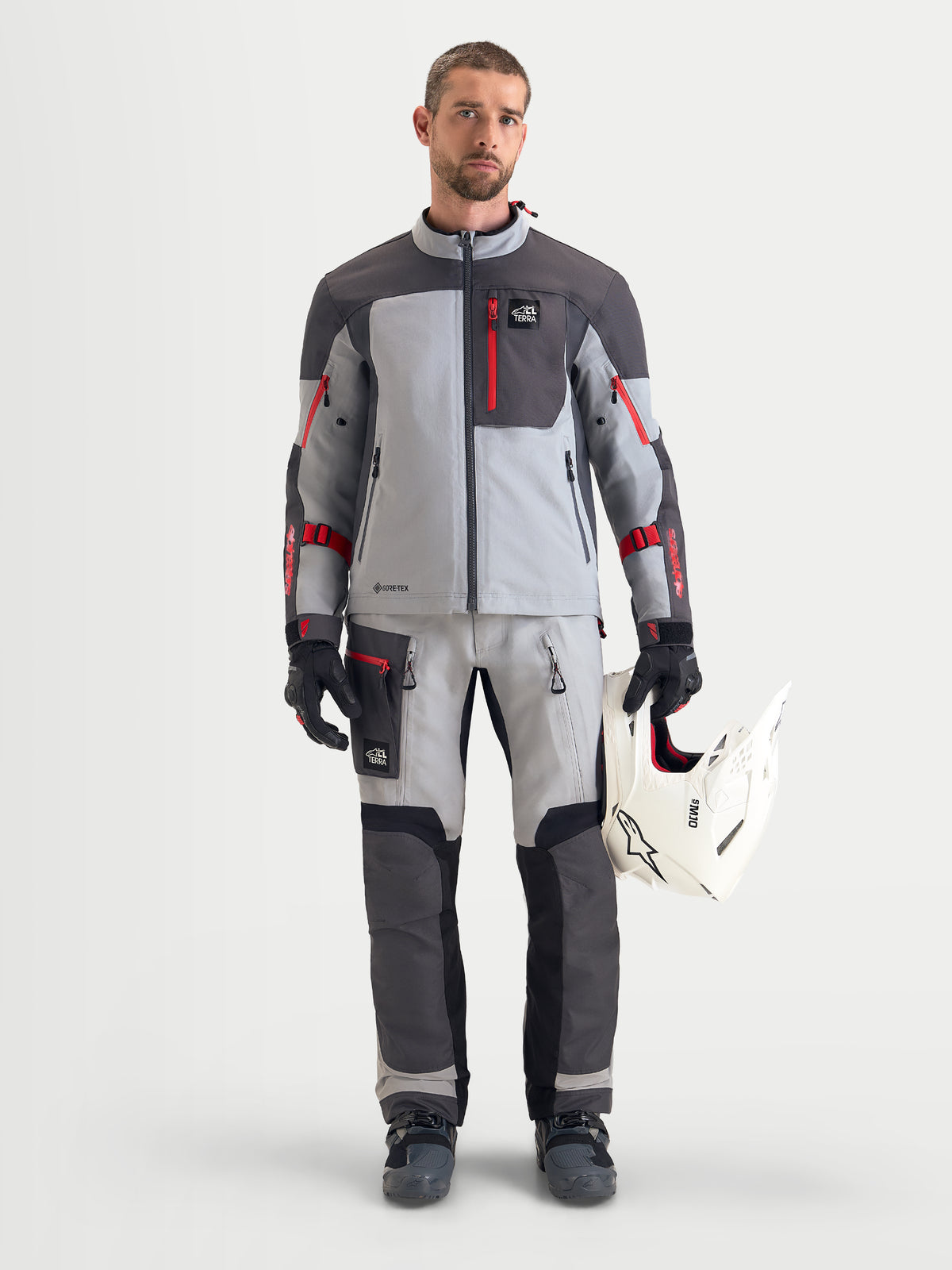 Alpinestars Arenis Gore-Tex bukser, herre adventure-motorcykelbukser, isgrå, mørkegrå og sort, frontvisning af mandlig model iført matchende jakke og hjelm, AA-certificeret vandtæt udstyr