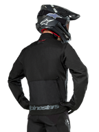 Alpinestars Pro-Dura jakke set bagfra, sort, holdbar ripstop-tekstil enduro-jakke, stor baglomme med gråt Alpinestars-branding nederst på ryggen, kombineret med en sort motocross-hjelm
