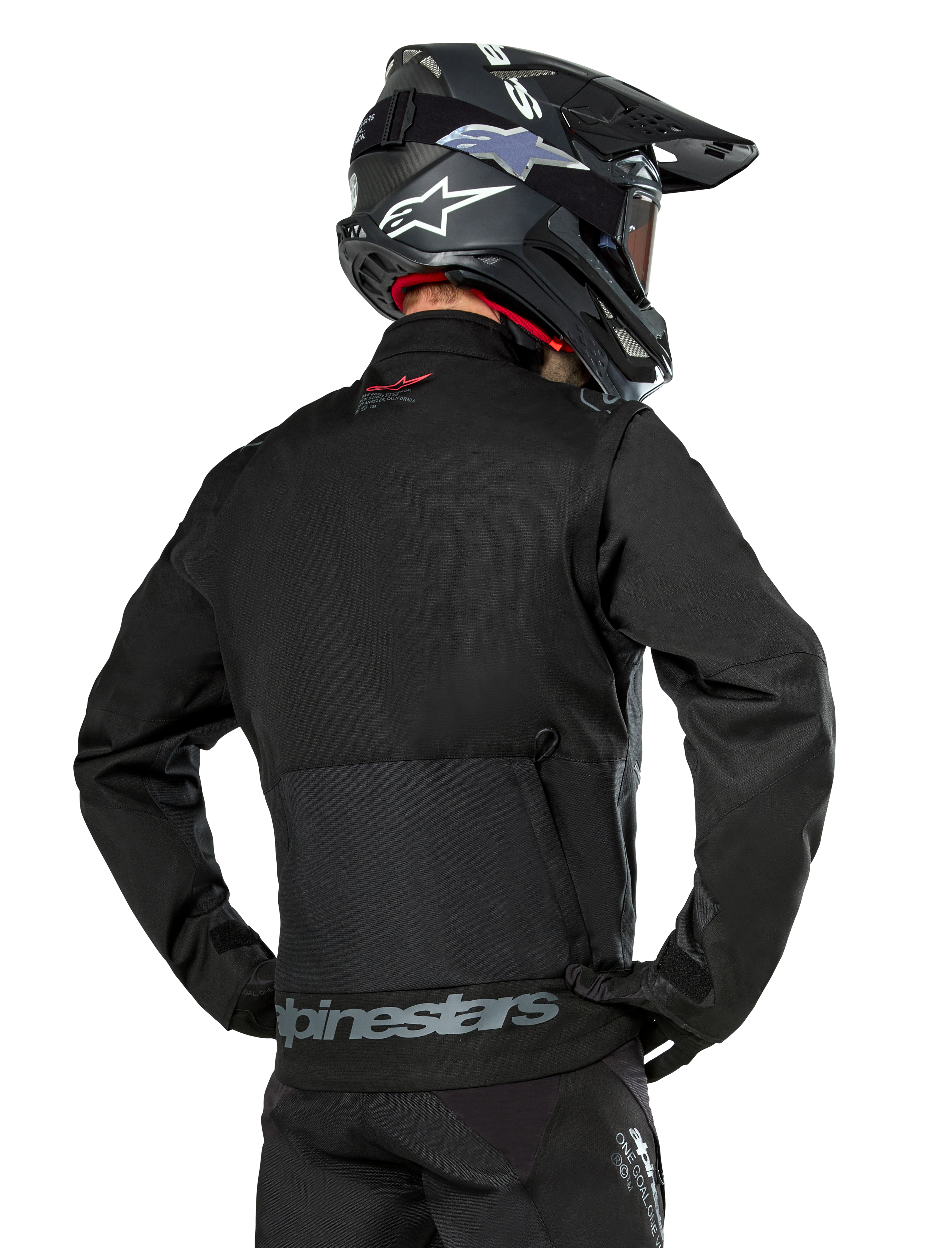 Alpinestars Pro-Dura jakke set bagfra, sort, holdbar ripstop-tekstil enduro-jakke, stor baglomme med gråt Alpinestars-branding nederst på ryggen, kombineret med en sort motocross-hjelm