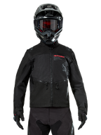 Alpinestars Pro-Dura jakke, sort off-road motorcykeljakke, set forfra båret af en kører med matchende sort hjelm og goggles, med rødt Alpinestars-logo, brystlommer med lynlås og holdbar tekstilkonstruktion til enduro-kørsel.