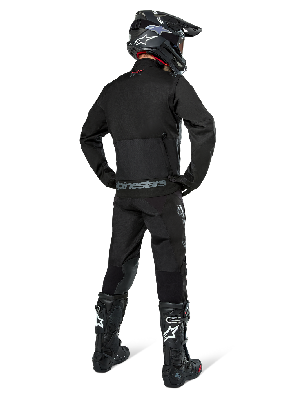 Alpinestars Pro-Dura jakke, sort off-road enduro-jakke, set bagfra båret med matchende bukser og sorte Tech 10-støvler, med fremtrædende Alpinestars-branding på den nederste del af ryggen, robust tekstilkonstruktion til aggressiv trail-kørsel
