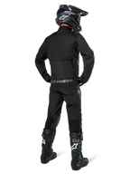 Alpinestars Pro-Dura jakke, sort off-road enduro-jakke, set bagfra båret med matchende bukser og sorte Tech 10-støvler, med fremtrædende Alpinestars-branding på den nederste del af ryggen, robust tekstilkonstruktion til aggressiv trail-kørsel