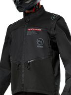 Alpinestars Pro-Dura-jakke, sort off-road motorcykeljakke med rødt Alpinestars-branding og et gråt cirkulært Astars-logo på brystet, lynlåslommer, holdbar ripstop-tekstilkonstruktion, rally-inspireret design til enduro-kørsel.