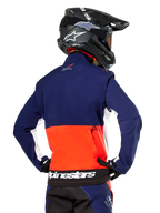 Alpinestars Lite-Dura Softshell Jacket, Navy Hot Orange and White, rear view worn by a motocross rider, featuring a large white logo on the back hem and zippered storage pocket, part of a complete off-road racing outfit.