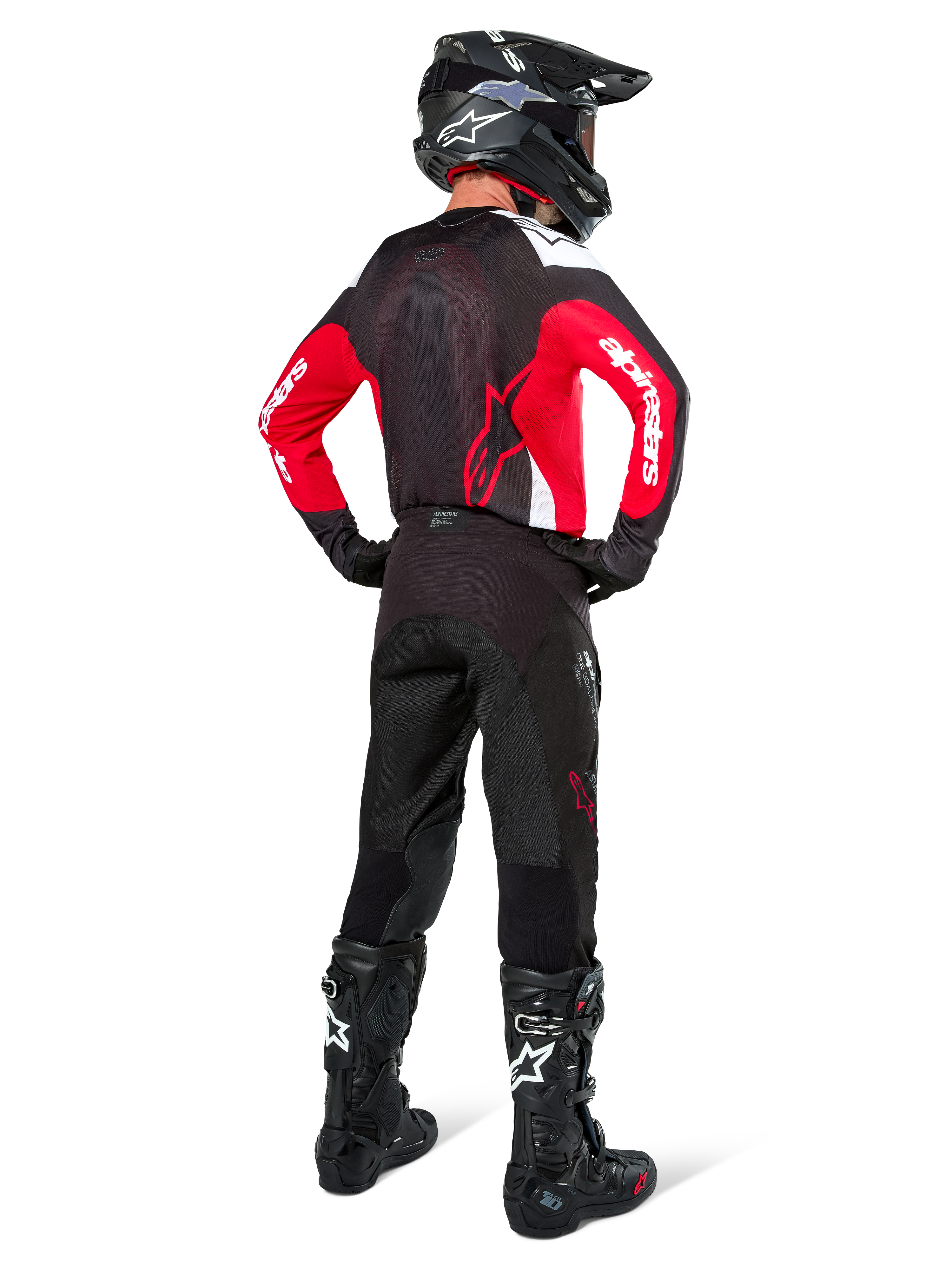Alpinestars Pro-Dura bukser i Black Magnet White, motocrossrytter set bagfra, kombineret med rød og sort trøje og sorte støvler, koordineret off-road udstyrssæt til enduro-kørsel