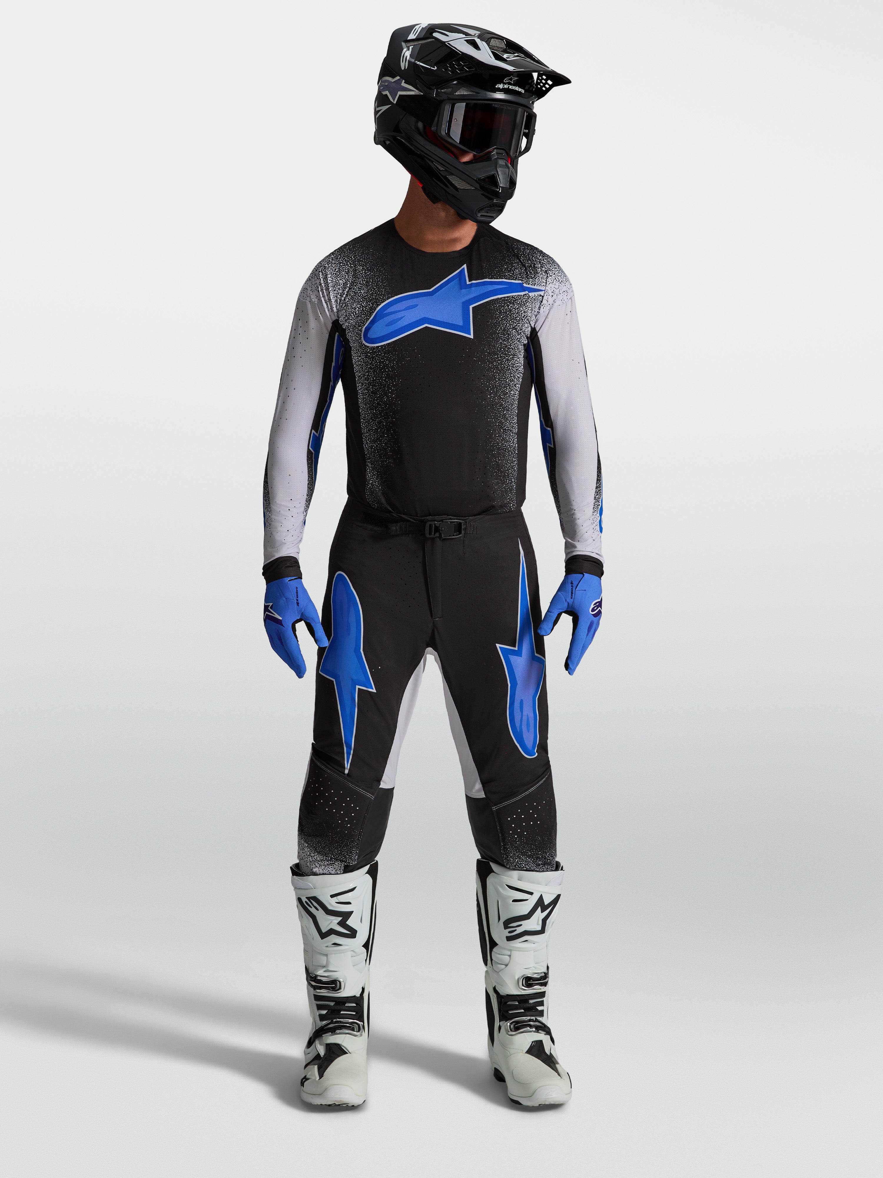 Alpinestars Supertech Hiten AFD Pants, black and blue motocross gear, on-model with matching jersey and white racing boots.