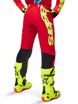 Alpinestars 2025 Supertech Maker Pants, Motocross Pants, Bright Red and Yellow Fluo, back view showing large yellow branding on the side and black panels on the lower legs, worn with coordinating fluo yellow boots and gear