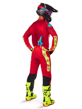 Alpinestars 2025 Supertech Maker Pants, Motocross Pants, Bright Red and Yellow Fluo, seen from behind on a rider wearing a matching red jersey, fluorescent yellow boots, and black helmet, featuring large yellow Alpinestars branding on the leg.