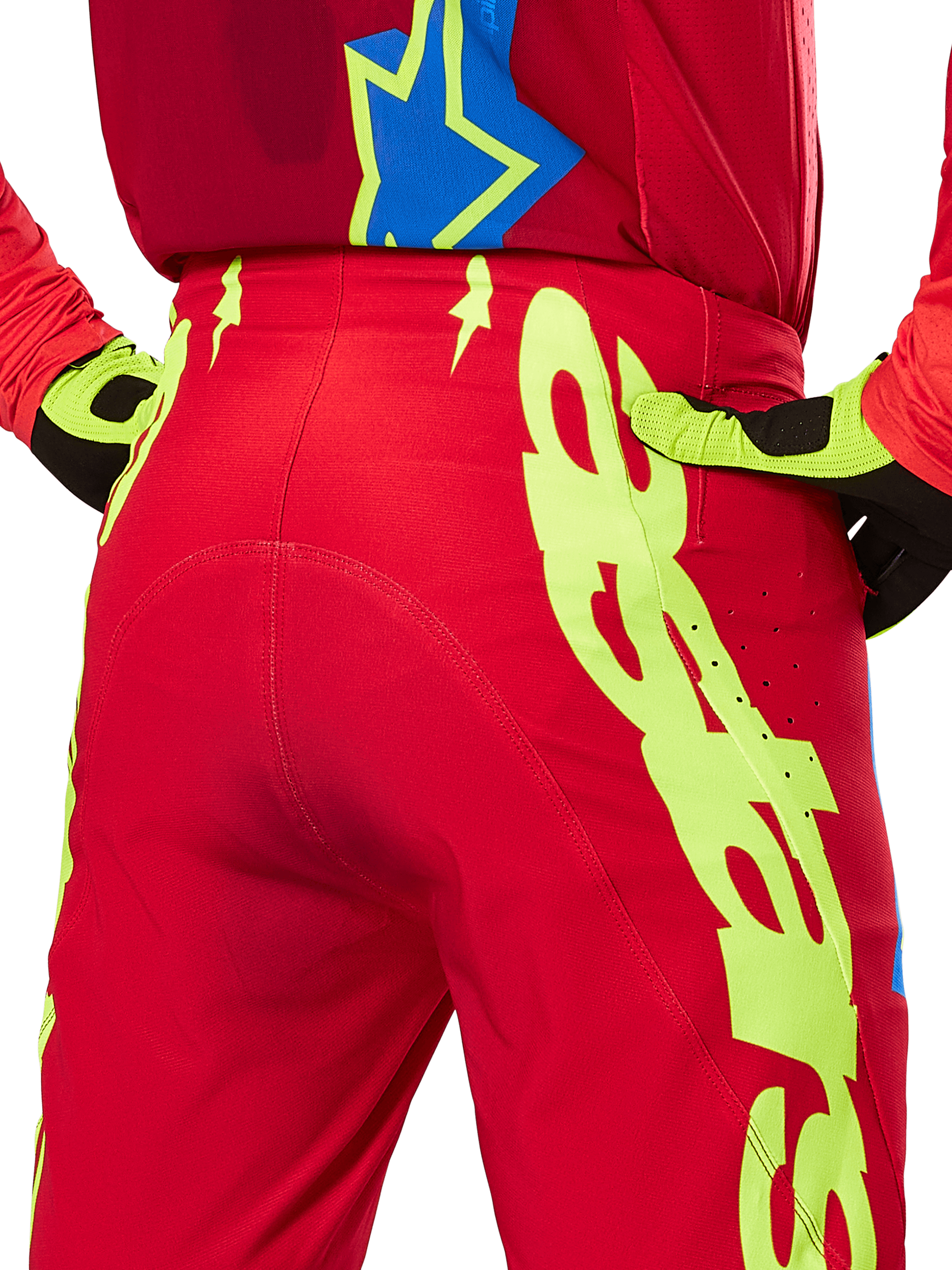 Alpinestars 2025 Supertech Maker bukser, motocross-bukser, klar rød og gul fluo, set bagfra med store gule grafikker på benene og matchende gul fluo og sorte handsker, professionelt racerudstyr til terrænkørsel