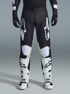 Alpinestars 2026 Racer Air Riway bukser, motocross-bukser, sort og hvid, med markante hvide Alpinestars-logoer på lårene og knæpanelerne, kombineret med hvide og sorte motocross-støvler og sorte handsker, atletisk race-fit design til off-road kørsel