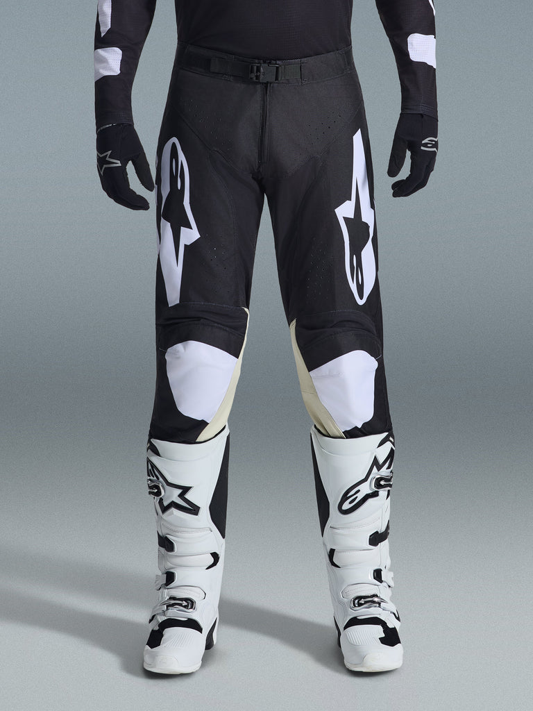 Alpinestars 2026 Racer Air Riway Pants, Motocross Pants, Black and White, featuring bold white Alpinestars logos on the thighs and knee panels, paired with white and black motocross boots and black gloves, athletic race-fit design for off-road riding