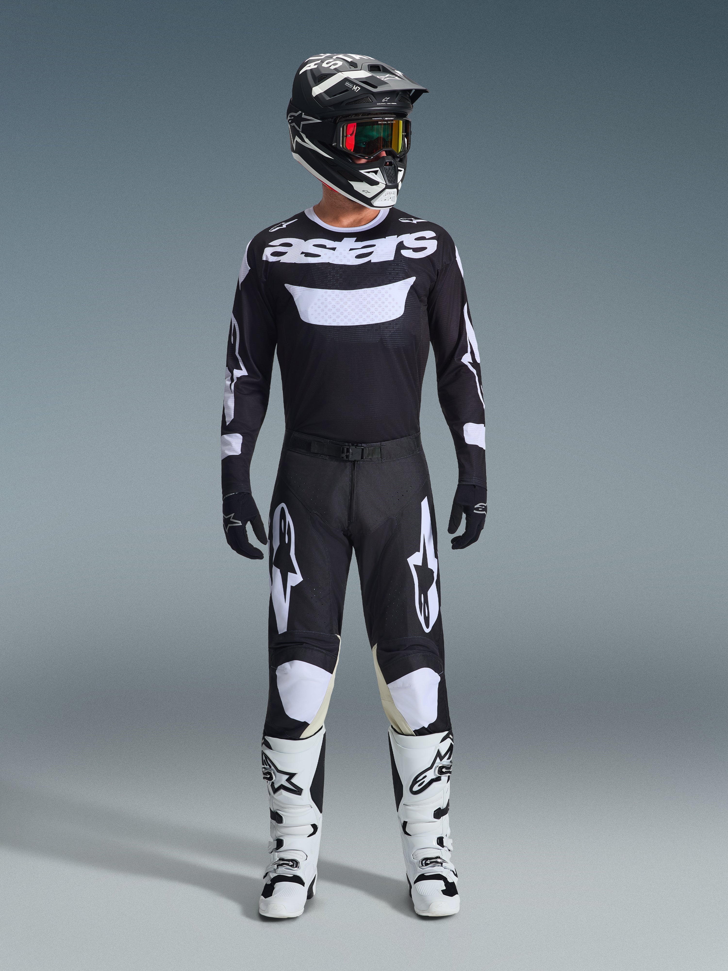 Motocross-kører iført Alpinestars 2026 Racer Air Riway bukser i sort og hvid, matchende sort og hvid jersey med 'astars'-logo, sort hjelm, goggles med iriserende linser og hvide racerstøvler, komplet professionelt off-road udstyrssæt