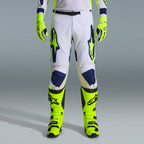Alpinestars 2026 Racer Air Riway Gear Set, Motocross Pants in White and Navy Blue with Neon Yellow accents, paired with matching neon yellow gloves and boots, featuring ergonomic design and ventilated panels for off-road racing.