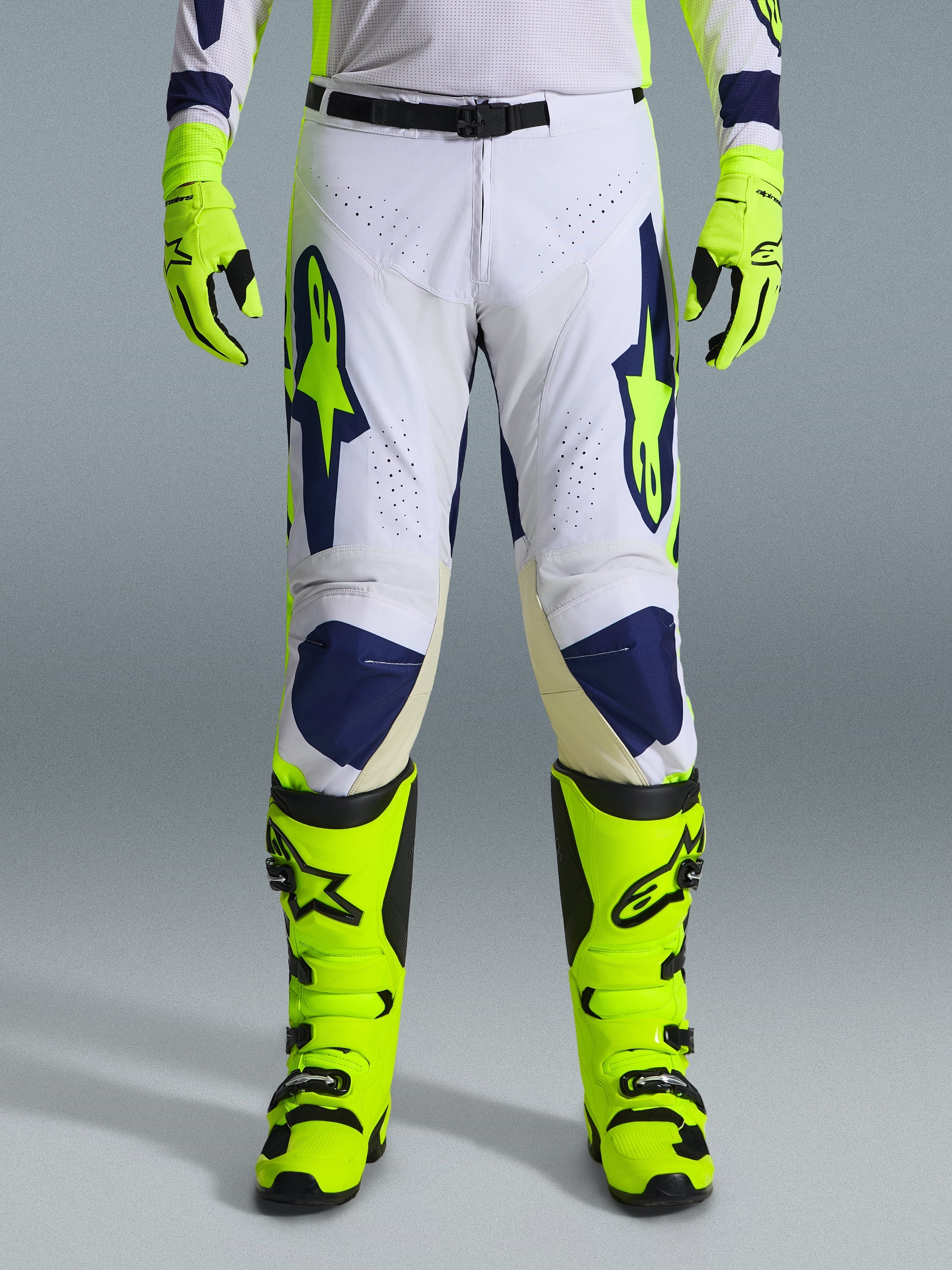 Alpinestars 2026 Racer Air Riway bukser, motocrossbukser, lysegrå, fluoriserende gul og blå, vist med matchende neongule handsker og støvler, med perforerede frontpaneler for luftstrøm og markant blå og gul branding, atletisk design til off-road ydeevne