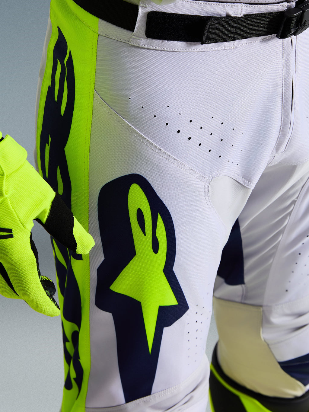 Alpinestars 2026 Racer Air Riway bukser, motocrossbukser, lys grå med gul fluo og blå accenter, nærbillede af lår med stort Alpinestars-logo og ventilationsperforeringer, holdbar race-fit konstruktion