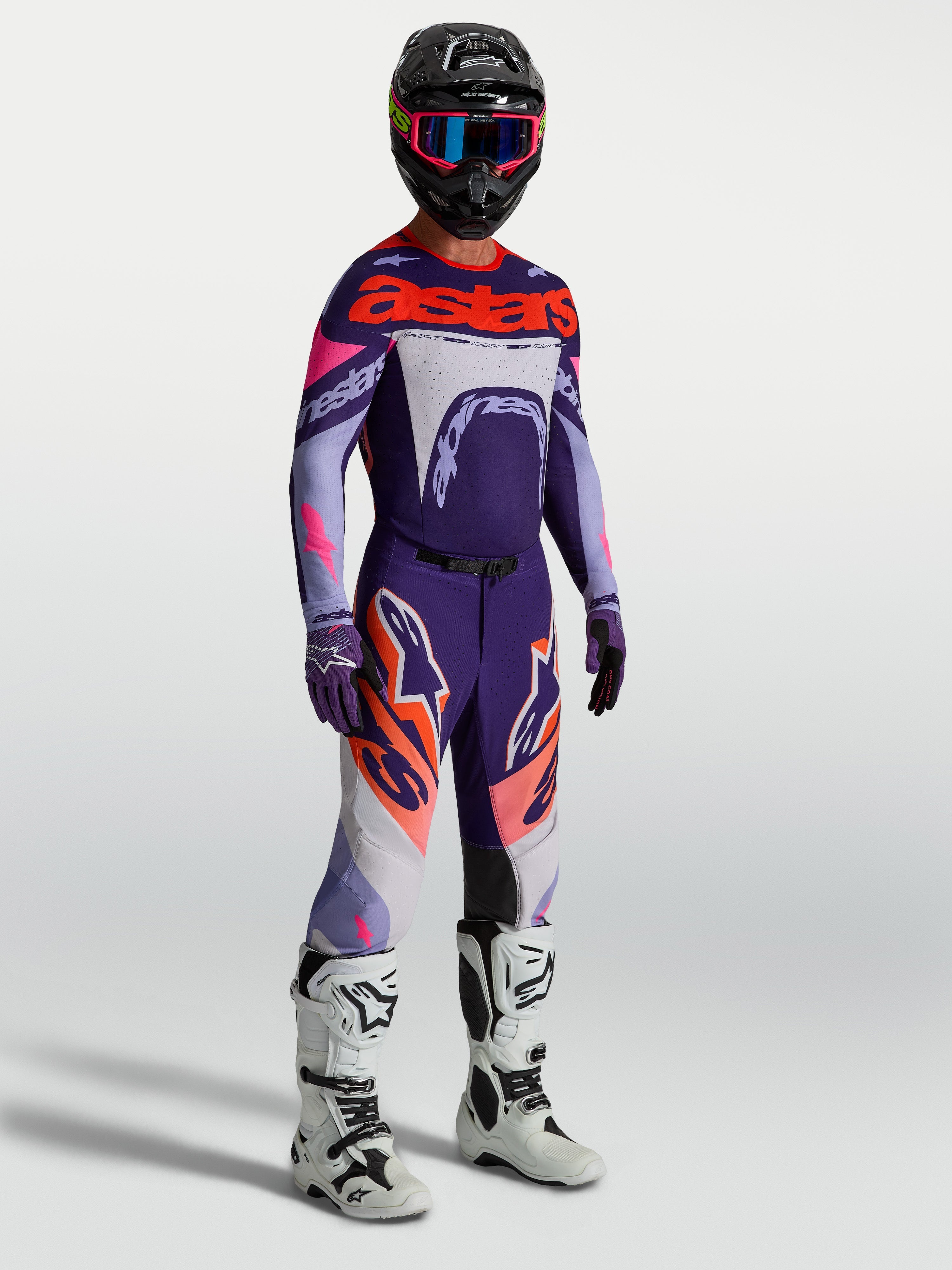 Alpinestars Supertech Dyna bukser i lilla og pink fluo, herre-motocrossudstyr med matchende trøje og hvide racingstøvler.