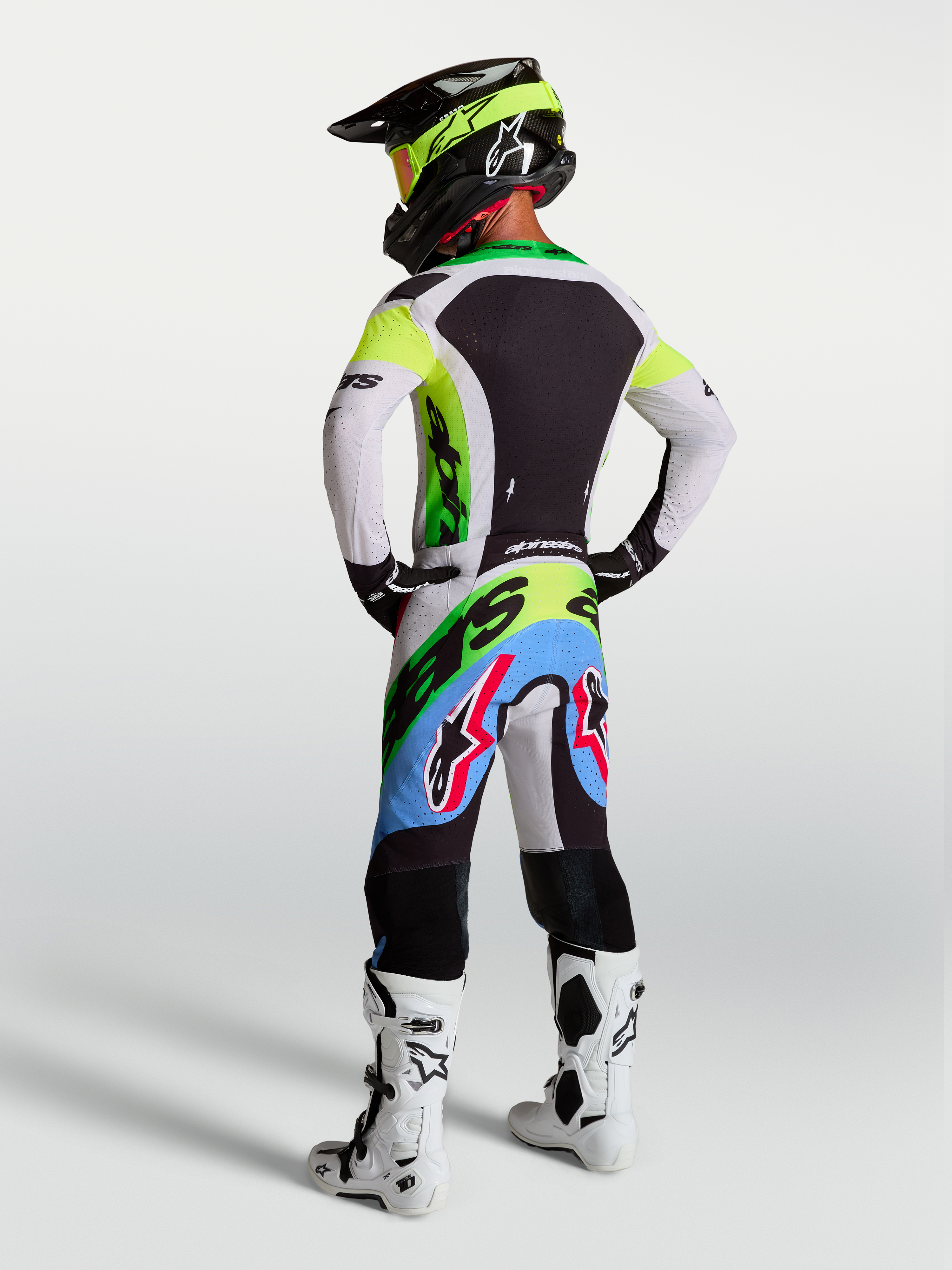 Alpinestars Supertech Dyna motocross gear in Green Fluo, Black, and Light Lilac, with racing pants and jersey, rear view.