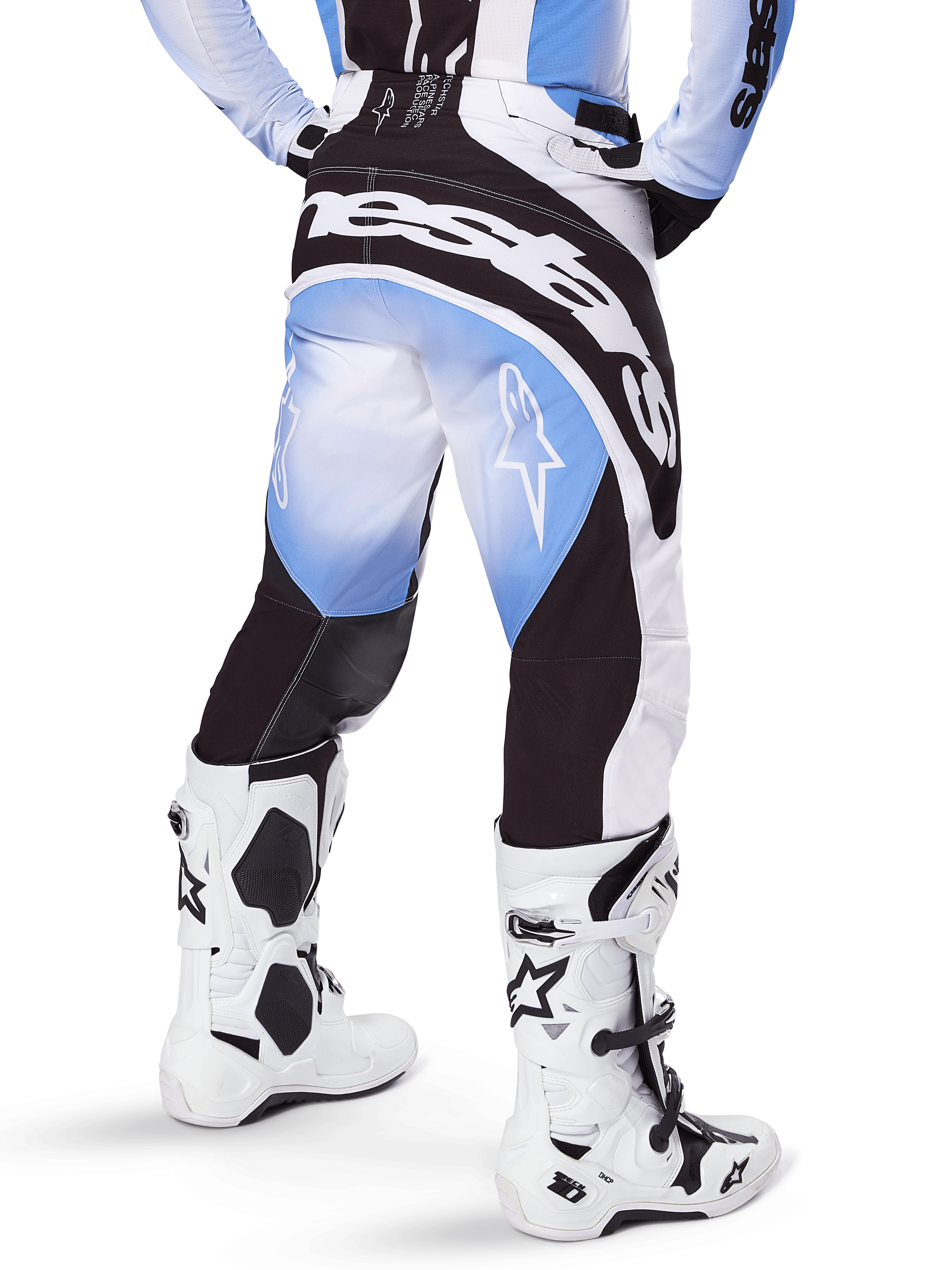 Alpinestars 2025 Techstar Melt Pants, Motocross Pants, Black Blue and White, rear view featuring bold Alpinestars wordmark across the seat and star logos on the legs, worn with white and black Tech 10 boots, professional off-road racing gear