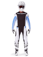 Motocross rider wearing Alpinestars 2025 Techstar Melt Pants, Motocross Pants, Black and Blue, white and black multi-panel design with blue hip accents, worn with matching white jersey, white helmet, white gloves, and boots for a complete off-road racing kit