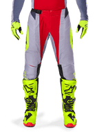 Alpinestars 2025 Techstar Melt bukser, motocrossbukser, rød og grå med neon gule detaljer, vist med matchende neon gule handsker og støvler, udstyret med magnetisk taljespænde og laser-skårne perforeringer til ventilation