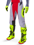 Alpinestars 2025 Techstar Melt bukser, motocross-bukser, rød og grå, med et markant neongult logo, båret med matchende neongule handsker og støvler, atletisk pasform til motocross-racing