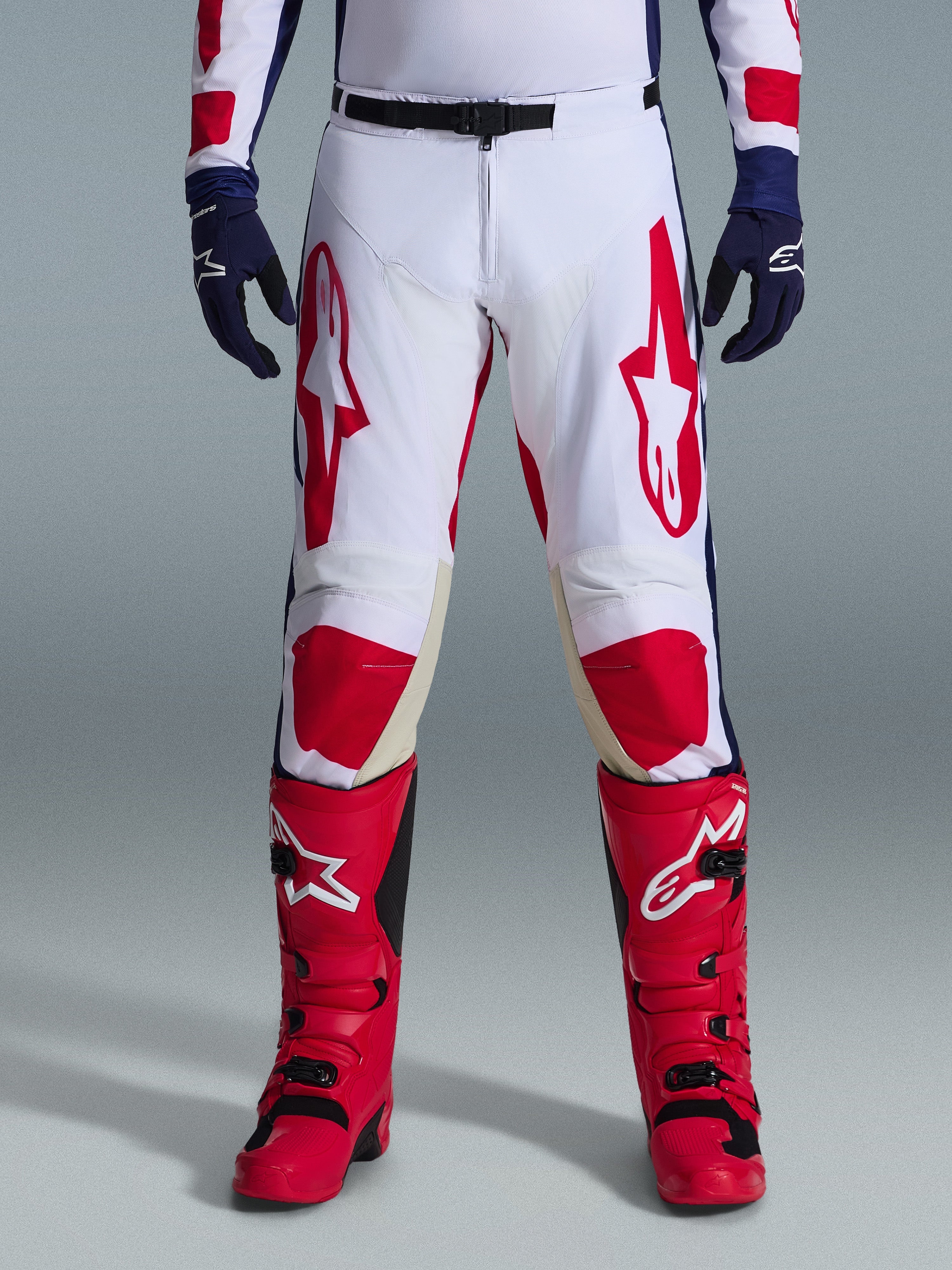 Alpinestars 2026 Racer Riway bukser, motocross-bukser, hvid, blå og rød, båret med røde støvler og mørkeblå handsker, med store røde logoer på lårene og røde knæpaneler, sportsligt forbuet design med justerbart taljespænde