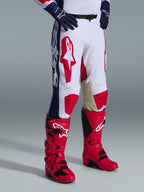 Alpinestars 2026 Racer Riway bukser, motocross-bukser, hvid, blå og rød, med markante røde logoer på lårene og blå sidepaneler med hvid branding, båret med røde støvler og mørkeblå handsker, ergonomisk design til off-road racing