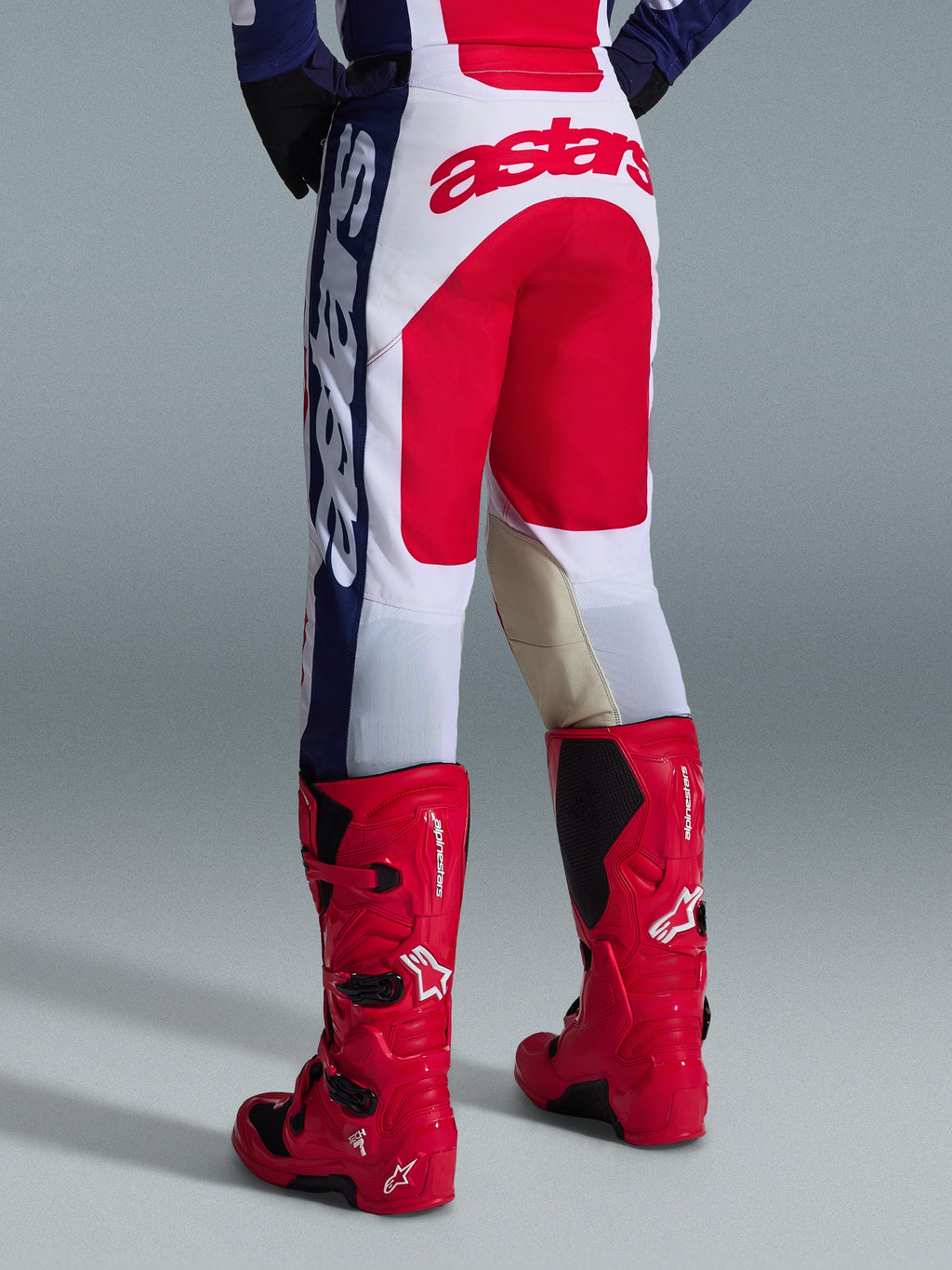 Alpinestars 2026 Racer Riway bukser, motocross-bukser, hvid, blå og rød, set bagfra med stort rødt Astars-logo på sædet og sandfarvede læderpaneler på indersiden af knæene, båret med røde Alpinestars motocross-støvler, præstationsudstyr til off-road kørsel