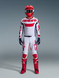 Motocross-rytter iført Alpinestars 2026 Racer Riway-udstyrssæt, hvid trøje med rød "astars"-branding og blå sidepaneler, hvide bukser med rød grafik, rød racerhjelm og støvler, mørkeblå handsker, komplet koordineret motocross-racerudstyr