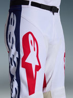 Alpinestars 2026 Racer Riway bukser, motocross-bukser, hvid, blå og rød, nærbillede af øverste del af ben og talje med stort rødt stjernelogo på hvidt polyfabric, blå sidepaneler med branding, sort justerbart taljebælte med SX2 magnetspænde, sporty off-road racerdesign