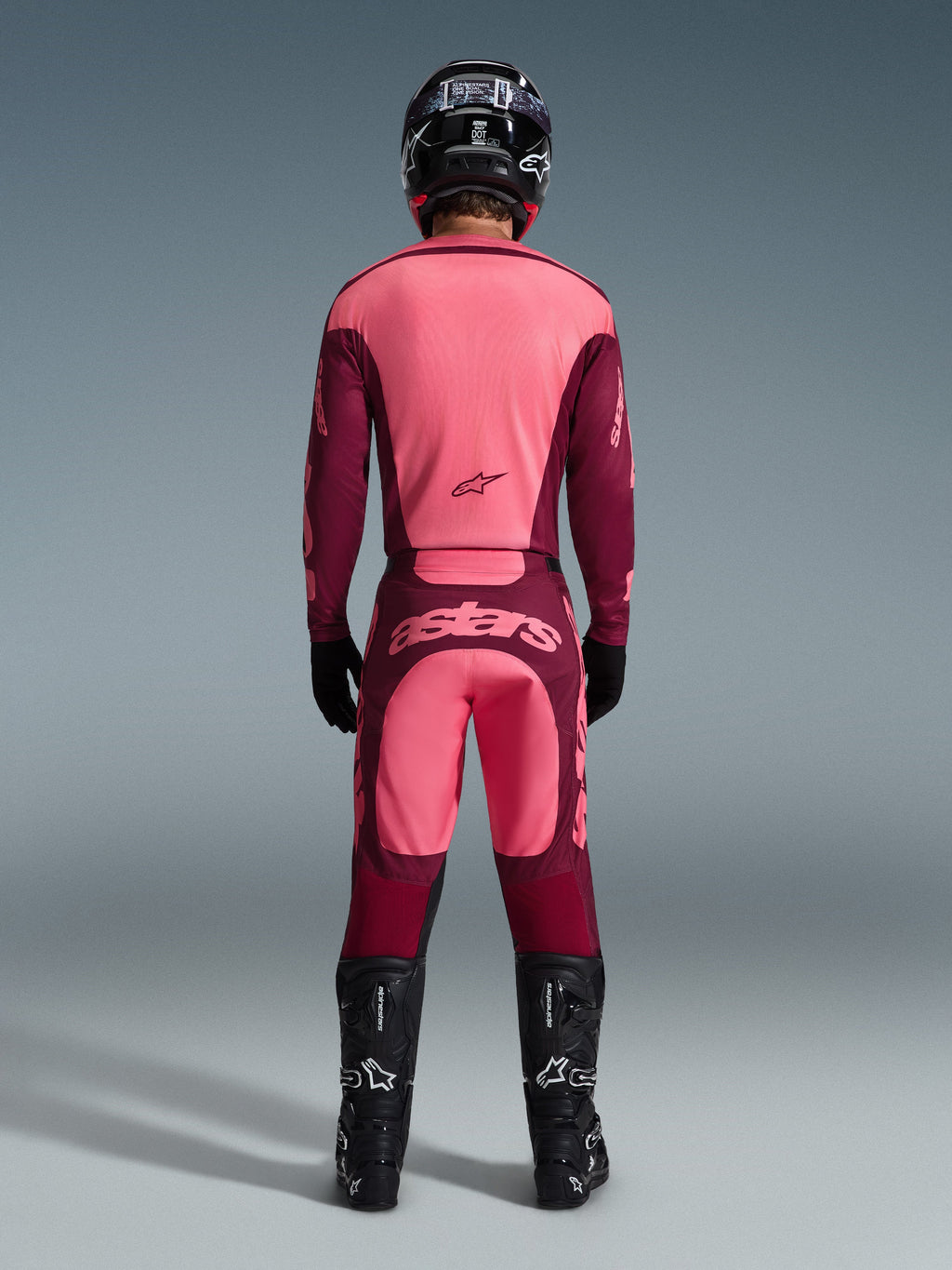 Motocrosskører set bagfra iført Alpinestars 2026 Racer Riway Jersey og matchende bukser i Dark Red Coral, med sorte støvler, en sort hjelm og sorte handsker, koordineret højpræstationsudstyr til off-road racing