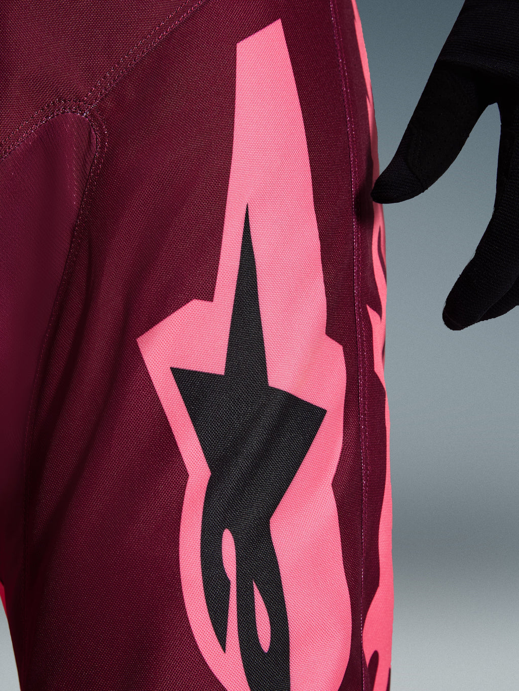Alpinestars 2026 Racer Riway bukser, motocross-bukser, Dark Red Coral, nærbillede der viser en stor koralrosa vinklet grafik og sort stjernelogo, der fremhæver den slidstærke polyfabric-tekstur og performance-syninger