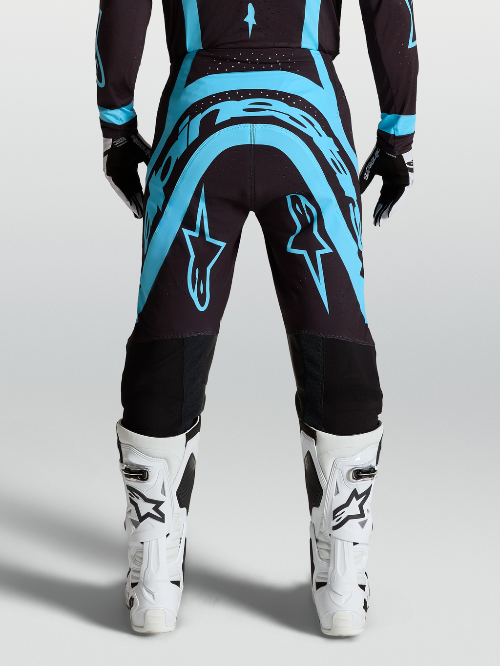 Alpinestars Supertech Vesta Motocross Pants, Black and Turquoise race-fit pants with White off-road riding boots.