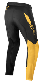 Alpinestars Supertech Blaze bukser, motocross-bukser, sort og varm gul, set bagfra fra siden, med markant 'ASTARS' logo på hoften, gule paneler på benet og teknisk strækmateriale til terrænkørsel