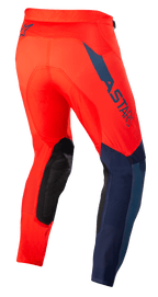 Alpinestars Supertech Blaze bukser, motocrossbukser, klar rød og mørkeblå, trekvart visning bagfra, med mørkeblåt ASTARS-logo på siden, sorte forstærkede knæpaneler og atletisk pasform til off-road kørsel.