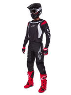 Motocross-kører iført komplet Alpinestars 2025 Fluid Haul-udstyrssæt, sort trøje med røde og hvide detaljer, sorte bukser med hvide logoer, stærkt røde støvler, røde og sorte handsker, sort hjelm med goggles, koordineret off-road-performanceudstyr