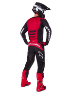 Motocrosskører iført Alpinestars 2025 Fluid Haul-udstyrssæt set bagfra, rød og sort trøje med hvid branding, matchende sorte bukser med røde detaljer, stærkt røde støvler og sort hjelm med hvide goggles, komplet koordineret outfit til off-road racing