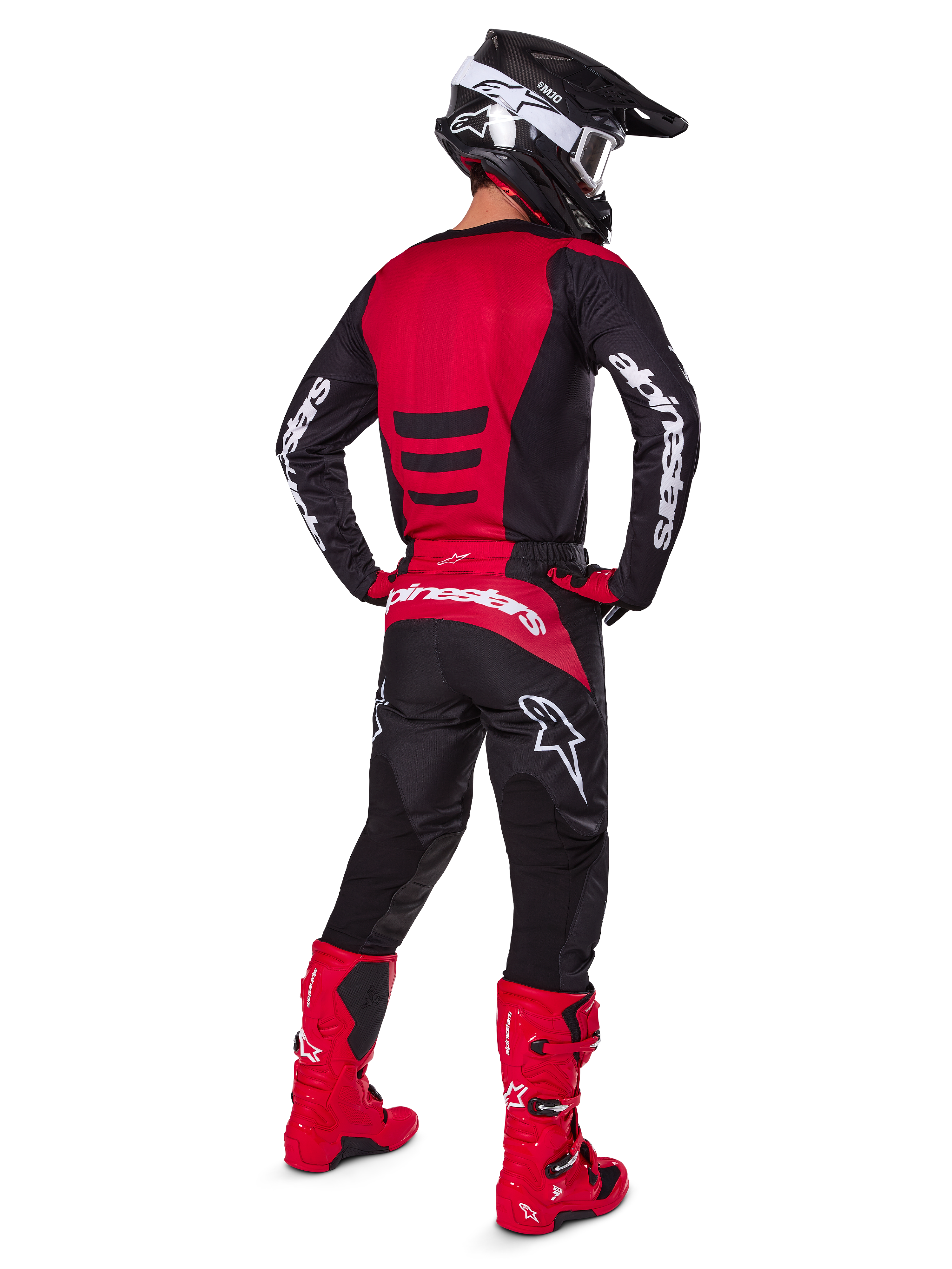 Motocrosskører iført Alpinestars 2025 Fluid Haul-udstyrssæt set bagfra, rød og sort trøje med hvid branding, matchende sorte bukser med røde detaljer, stærkt røde støvler og sort hjelm med hvide goggles, komplet koordineret outfit til off-road racing