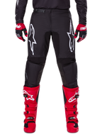 Alpinestars 2025 Fluid Haul udstyrssæt, sorte motocrossbukser med hvide Astars-logoer på lårene, kombineret med stærke røde støvler og røde og sorte handsker, koordineret motocross-outfit til terrænkørsel