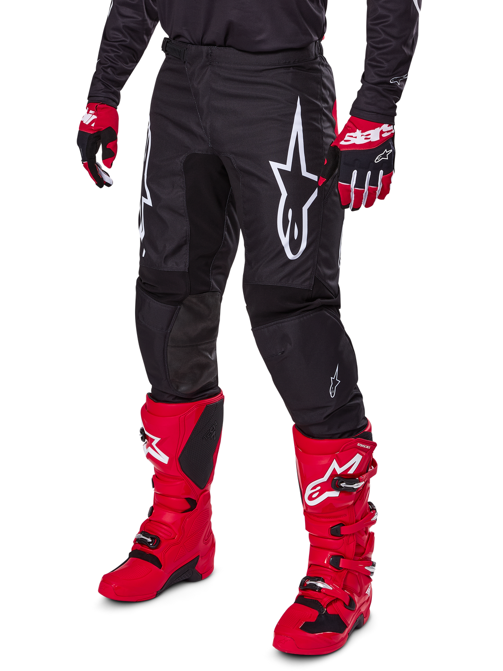Alpinestars 2025 Fluid Haul bukser, motocross-bukser, sort, med et stort hvidt Alpinestars-logo, båret med stærkt røde støvler og røde og sorte handsker, holdbar 600D polyfabrik-konstruktion med ergonomisk snit til off-road kørsel