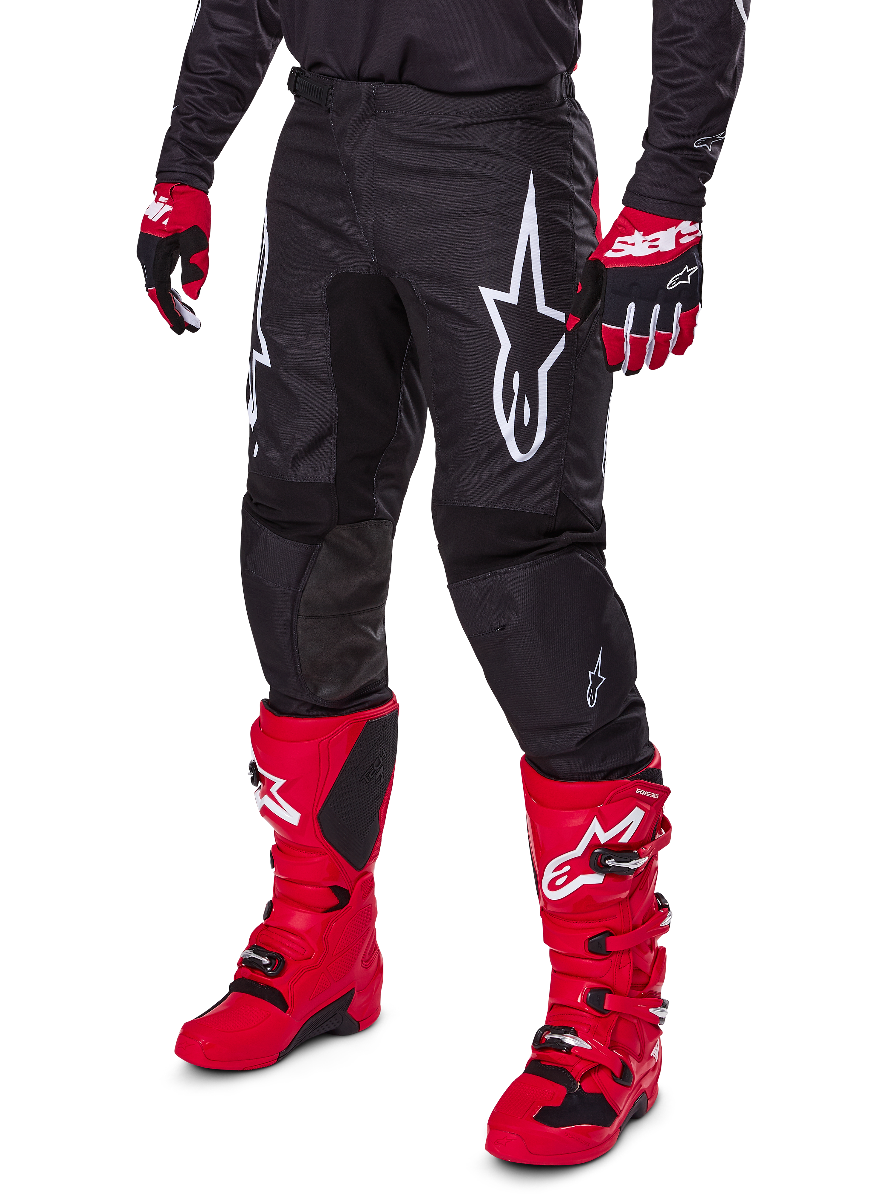 Alpinestars 2025 Fluid Haul bukser, motocross-bukser, sort, med et stort hvidt Alpinestars-logo, båret med stærkt røde støvler og røde og sorte handsker, holdbar 600D polyfabrik-konstruktion med ergonomisk snit til off-road kørsel