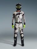 Motocrosskører iført Alpinestars 2026 Racer Lahnd Gear Set, Sand Camo-mønstret dragt med hvidt, gråt og sort design, sort hjelm med neongrønne goggles, stærke neongrønne handsker og sorte støvler med hvide logoer, komplet koordineret outfit til off-road racing