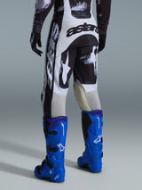 Alpinestars 2026 Racer Lahnd bukser, motocrossbukser, Iron Camo gråt og sort mønster, set bagfra med stort hvidt og sort astars-branding, kombineret med klare blå motocross-støvler, professionelt off-road racerudstyr